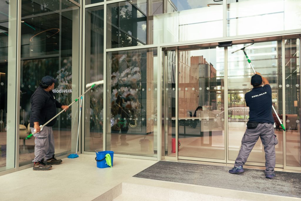 Dos personas limpiando ventanas exteriores.