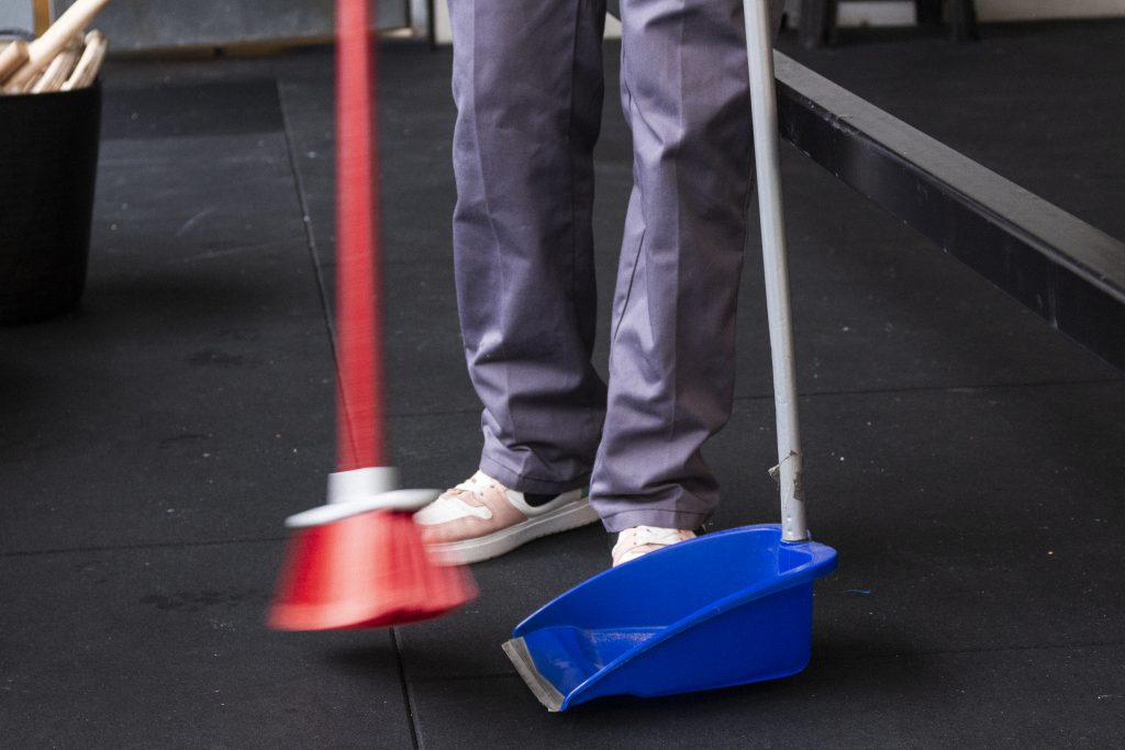 Persona limpiando con escoba y recogedor
